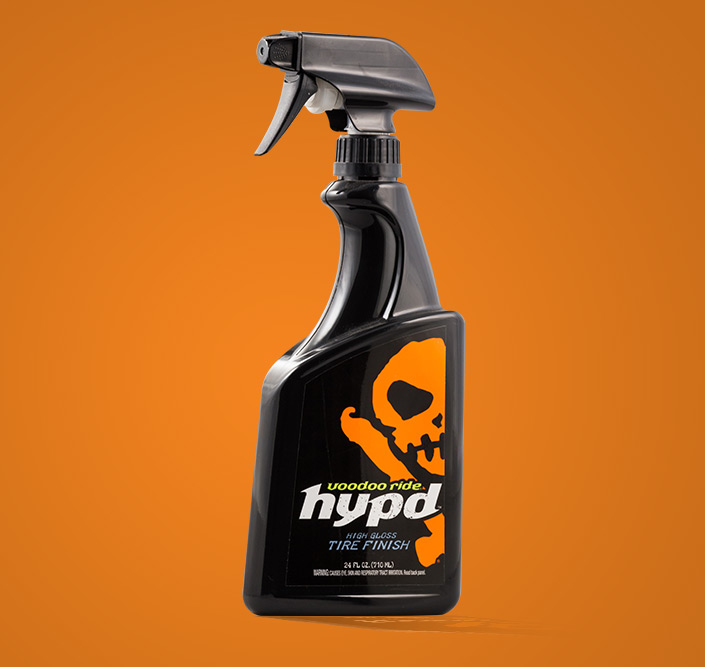 Black bottle and label of Voodoo Ride Tire cleaner on orange background