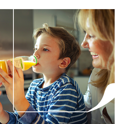 Boy drinking juice from a custom labeled juice bottle with mother