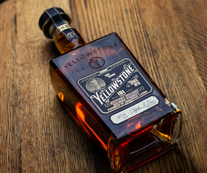 Yellowstone whiskey bottle with gold foiled custom label on wood background