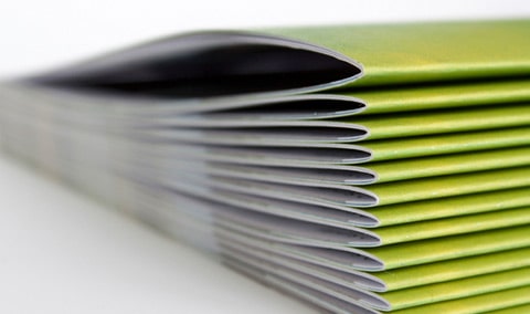 A stack of sage green printed inserts