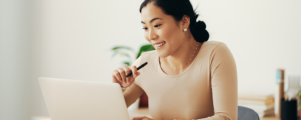 A smiling woman works on a laptop