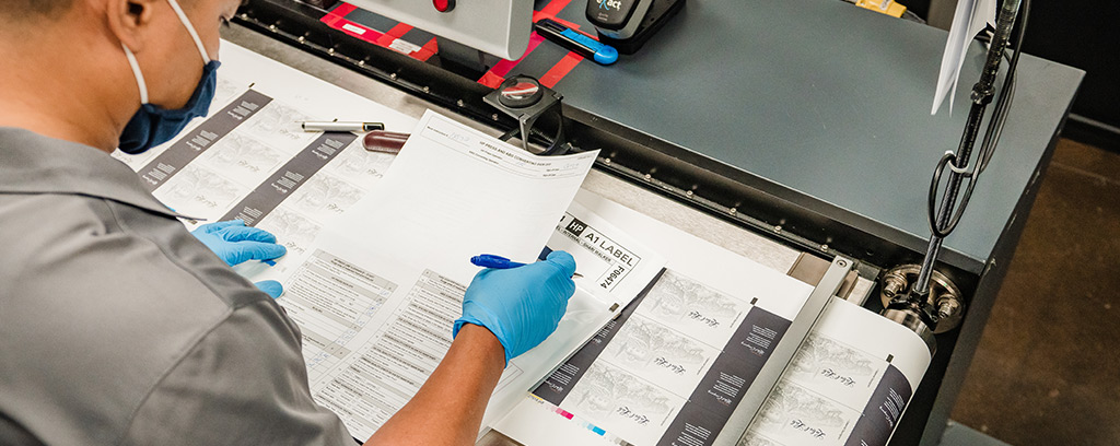 A press operator performs a quality check on a label run