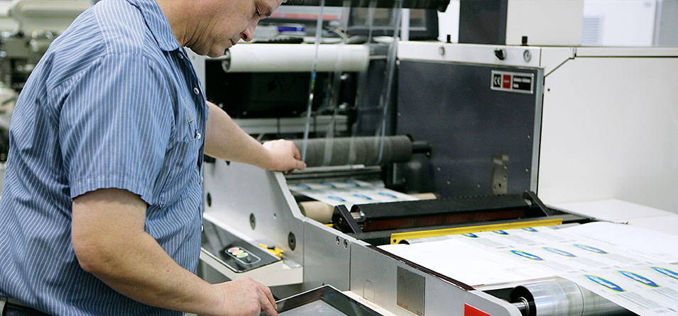 Man running custom labels through printing press