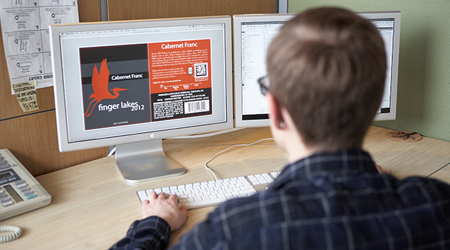 A graphic designer works on label artwork on a computer