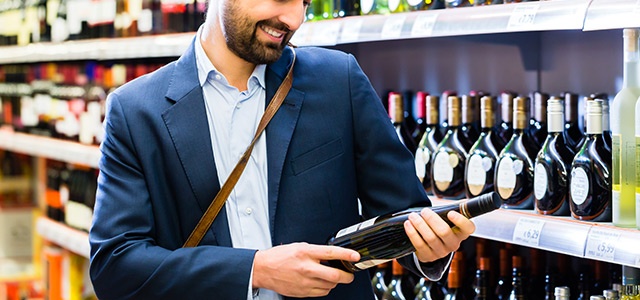 Shopper selecting wine off of the store shelf.